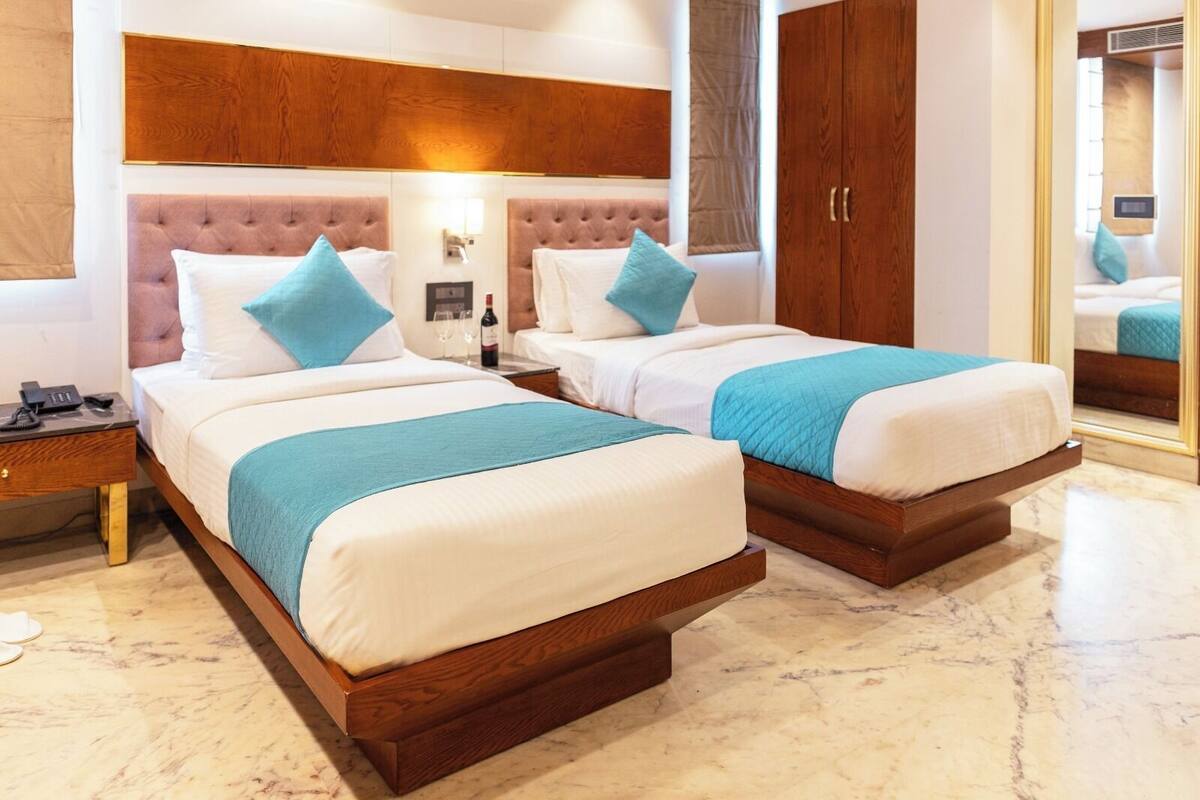 Ein Hotelzimmer mit zwei Betten, einem Holzkopfstück, einem Nachttisch, einem Spiegel und einem Kleiderschrank.