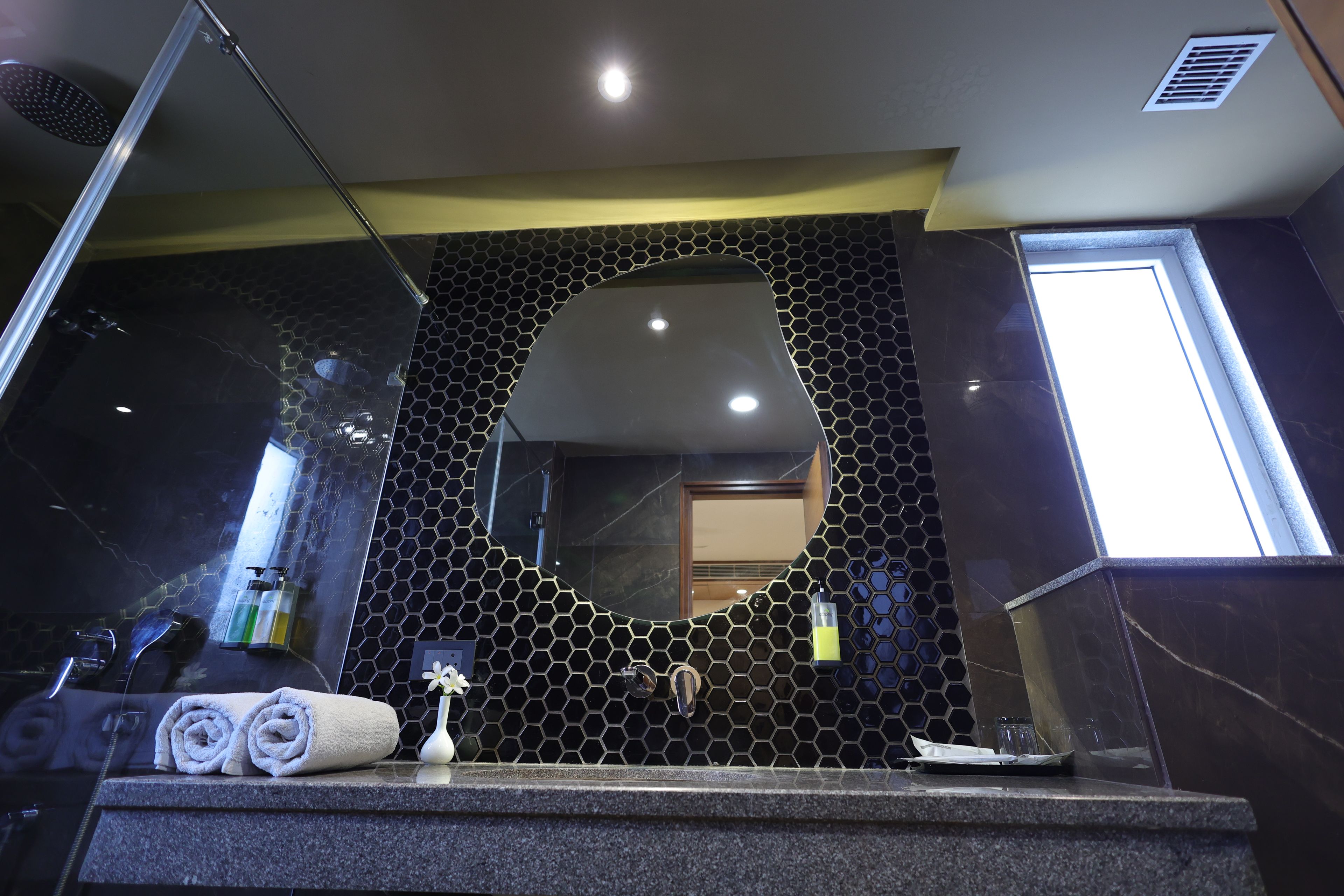 Un baño con un espejo grande, una toalla y artículos de aseo en el mostrador.