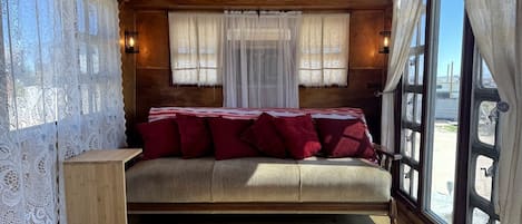 A cozy cabin-style room with a bed, a small wooden table, and large windows.