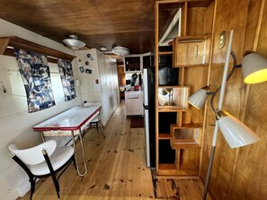 A kitchen with wooden cabinets, a stove, and a dining area with a table and chairs. - Retro Trailer Rental for Glamping Getaway in Joshua Tree, California (Joshua Tree)