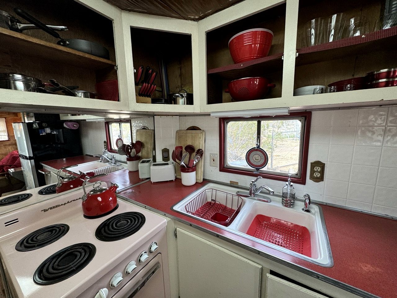 A compact kitchen with a stove, sink, and various utensils.