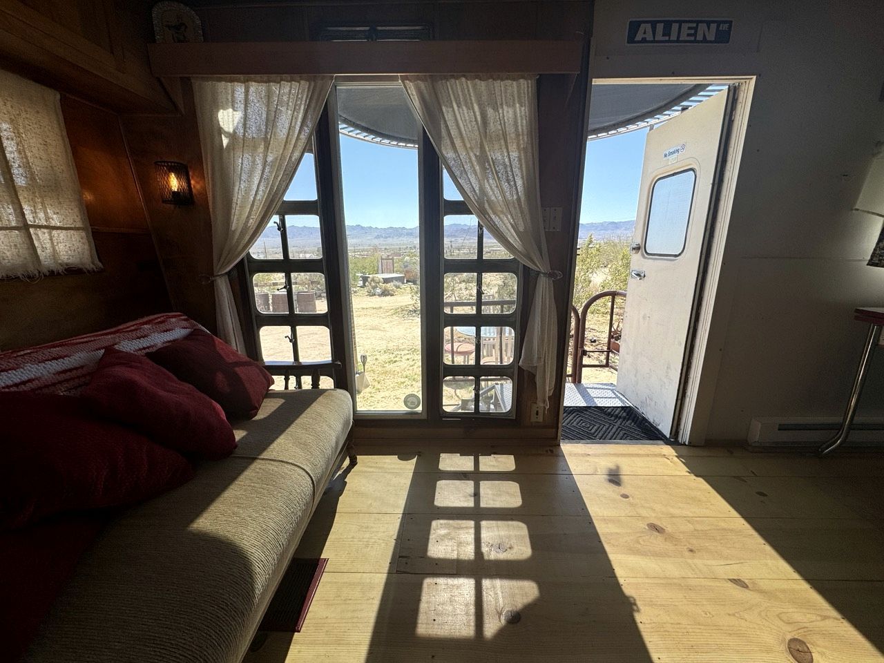 Una stanza con un letto, una finestra con tende e una porta che dà sull'esterno.