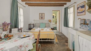 Una habitación con una cama, una mesa con un florero y una ventana con cortinas.