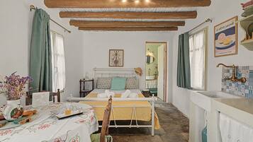 Una habitación con una cama, una mesa con un florero y una ventana con cortinas.