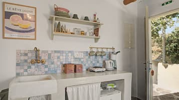 Una cocina con salpicadero de azulejos, un colgador para ollas y una puerta que da al exterior.