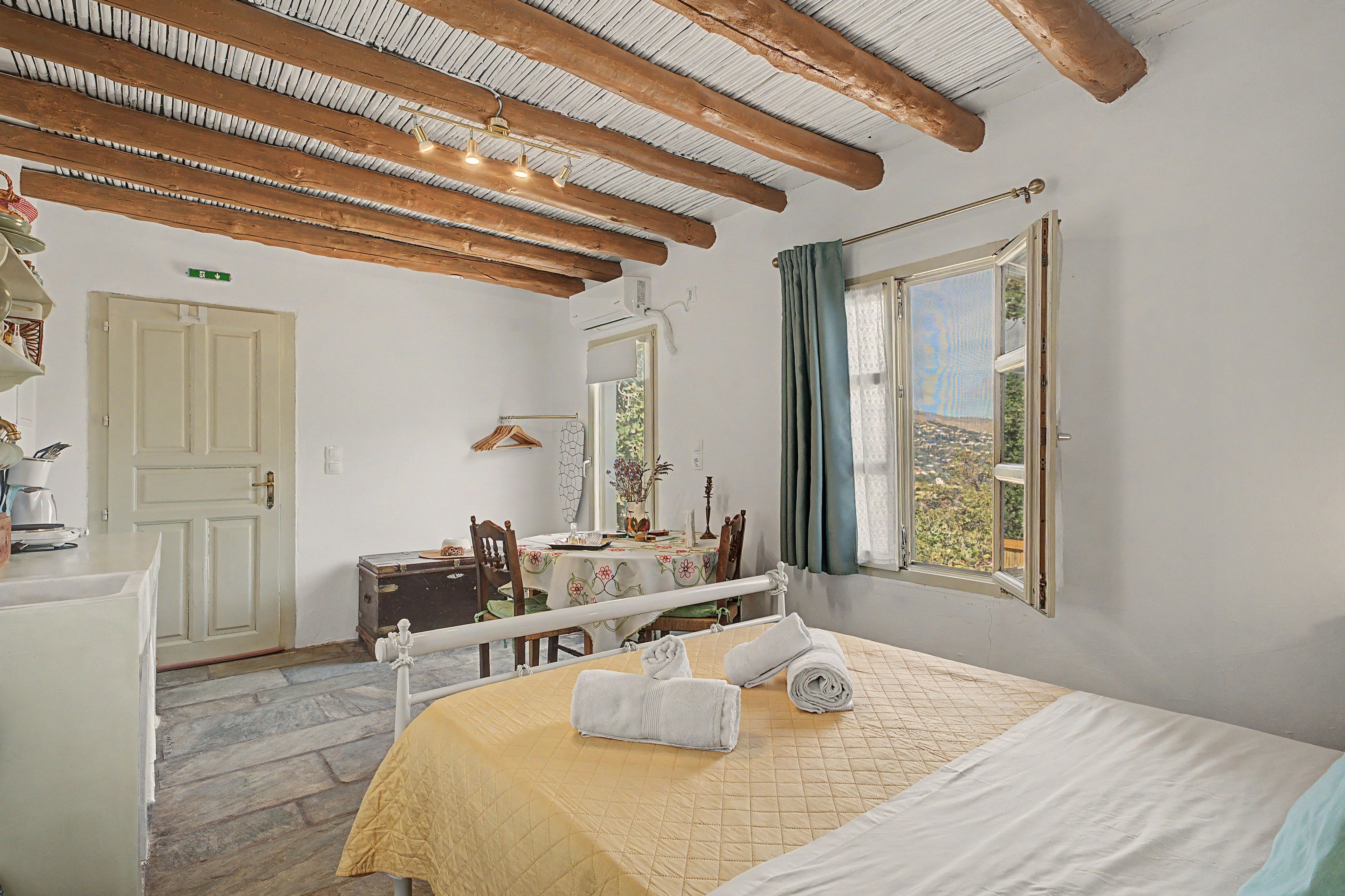 Una camera da letto con un letto, una cassettiera, una scrivania, una sedia, una finestra con tende e vista sull'esterno.