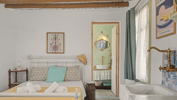Un dormitorio con cama, mesita de noche, espejo, lavabo y bañera.