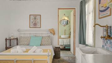 A bedroom with a bed, a bedside table, a mirror, a sink, and a bathtub.