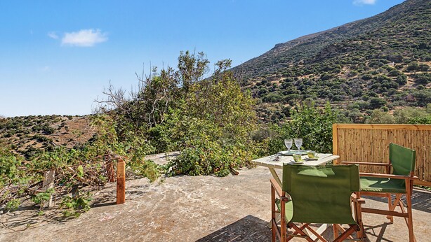 Une terrasse avec une table et des chaises, offrant une vue sur un paysage montagneux.