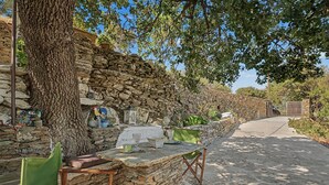 Un espacio de descanso al aire libre de estilo rústico con paredes de piedra, una mesa de madera y una silla.