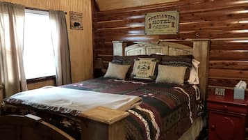 Une pièce de style cabane en bois, avec un lit, une table de chevet et une fenêtre avec des rideaux.