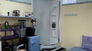 A compact room with a kitchenette, a small table, a sofa, and a window.