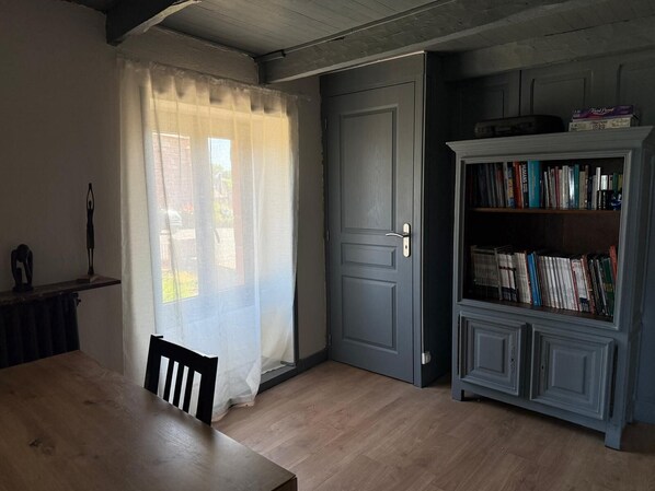 A room with a wooden table, a chair, a bookshelf, and a door.