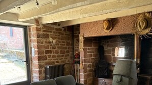A living room with a brick wall, a fireplace, a sofa, a coffee table, and a stone fireplace surround.
