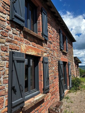 A stone building with multiple windows and shutters.