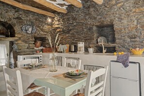 Una cocina rústica con paredes de piedra, una mesa de comedor para dos personas y una cafetera.