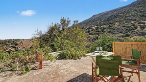 Eine Terrasse mit Tisch und Stühlen mit Blick auf eine gebirgige Landschaft.