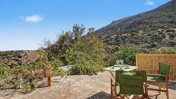 Un patio con mesa y sillas, con vista a un paisaje montañoso.