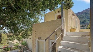 A staircase leading to a building with a textured wall and a door. - Oak Farm Traditional Family House (Andros)
