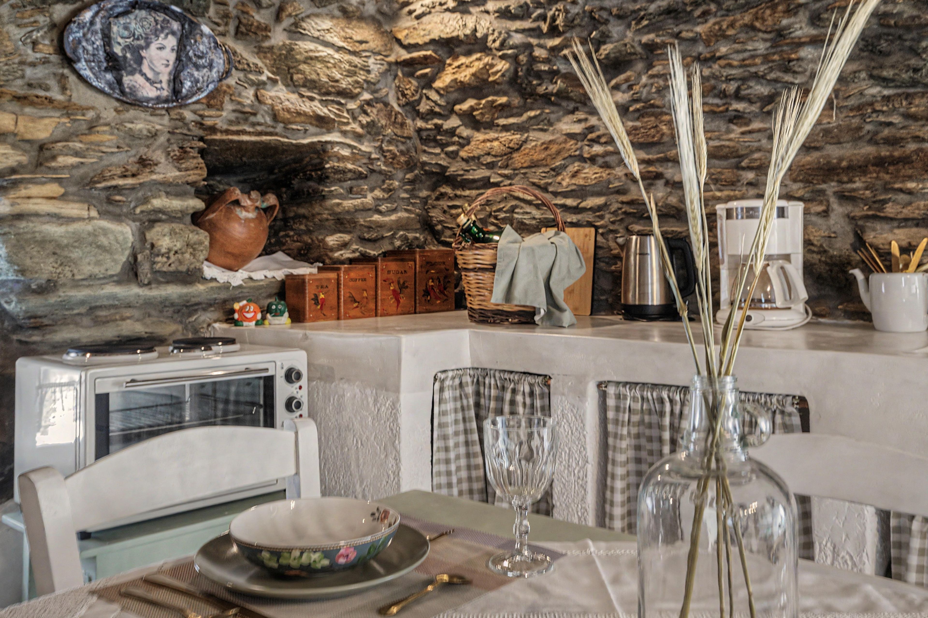 A rustic kitchen with stone walls, a vintage toaster, and a vase with reeds on the table.