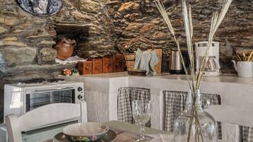 A rustic kitchen with stone walls, a vintage toaster, and a vase with reeds on the table.