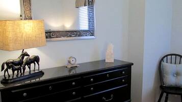 Une commode noire à tiroirs, un miroir avec un cadre orné, une lampe et une petite horloge.