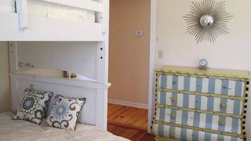 A bedroom with bunk beds, a dresser, and a decorative wall piece.