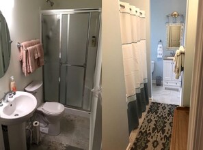 Un baño con ducha, inodoro, lavamanos y espejo.