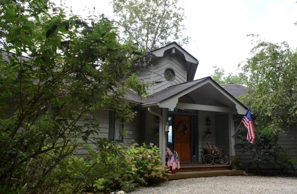 Une maison avec un porche à l’avant, une porte en bois et un drapeau américain.
