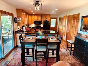 A kitchen with wooden cabinets, a dining table with chairs, a refrigerator, and a microwave. - Amazing Cottage with Fire Pit and Hot-tub in Lake Santeetlah, North Carolina (Lake Santeetlah)