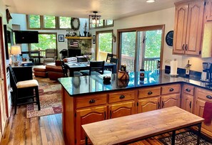 A spacious kitchen with a large island, wooden cabinets, and a stone fireplace.