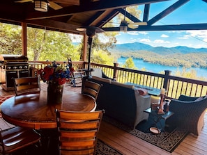 Une terrasse extérieure couverte, avec une table en bois, des chaises et un barbecue.