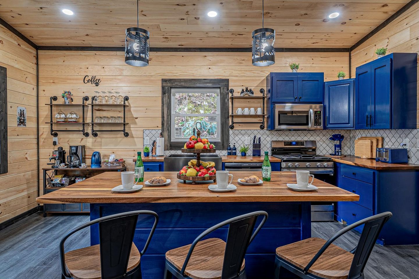 A modern kitchen with a central island, blue cabinets, and a coffee bar.