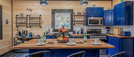A modern kitchen with a central island, blue cabinets, and a coffee bar.