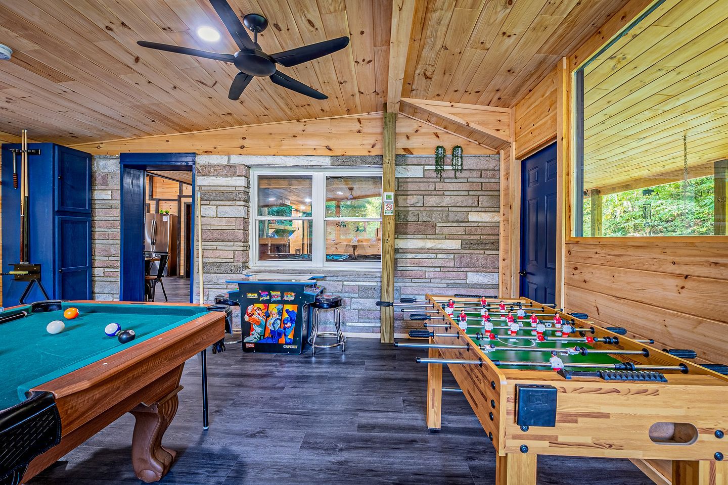 Una habitación con suelo de madera, mesa de billar, mesa de fútbol de mesa y mesa de billard.