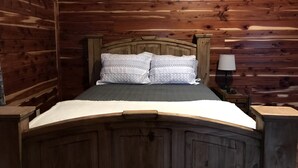 Un letto con struttura in legno, due cuscini, un comodino con una lampada e un soffitto in legno.