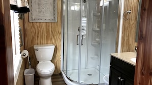 Un bagno compatto con il water, una cabina doccia in vetro e un mobile lavabo in legno.