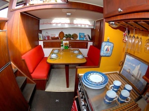 A compact galley with a wooden table, red cushioned seating, and a stove.