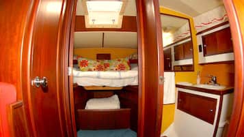A compact, wood-finished interior with a bunk bed, a small bathroom with a sink, and a mirror.