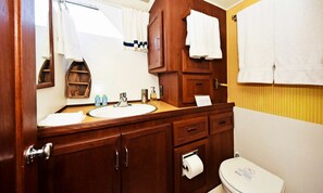 Ein Badezimmer mit einem Holzkosmetikschrank, einem Waschbecken, einem Spiegel, einer Toilette und einem Handtuchhalter.