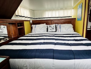 A bed with a striped bedspread, wooden headboard, and curtains.
