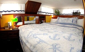 Ein Schlafzimmer mit einem Bett, einem Nachttisch, einem Spiegel und einem Fenster mit Vorhängen.