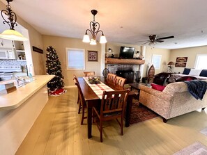 A dining area with a wooden table and chairs, a Christmas tree, a fireplace, and a sofa. - Cozy Cabin Rental near Table Rock Lake in the Ozark Mountains, Missouri (Hollister)