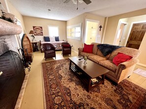 A living room with a sofa, armchairs, a coffee table, a patterned rug, and a fireplace. - Cozy Cabin Rental near Table Rock Lake in the Ozark Mountains, Missouri (Hollister)