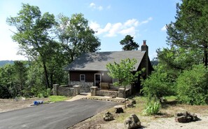 Une cabane rustique avec des fondations en pierre, un toit en pente et une cheminée.