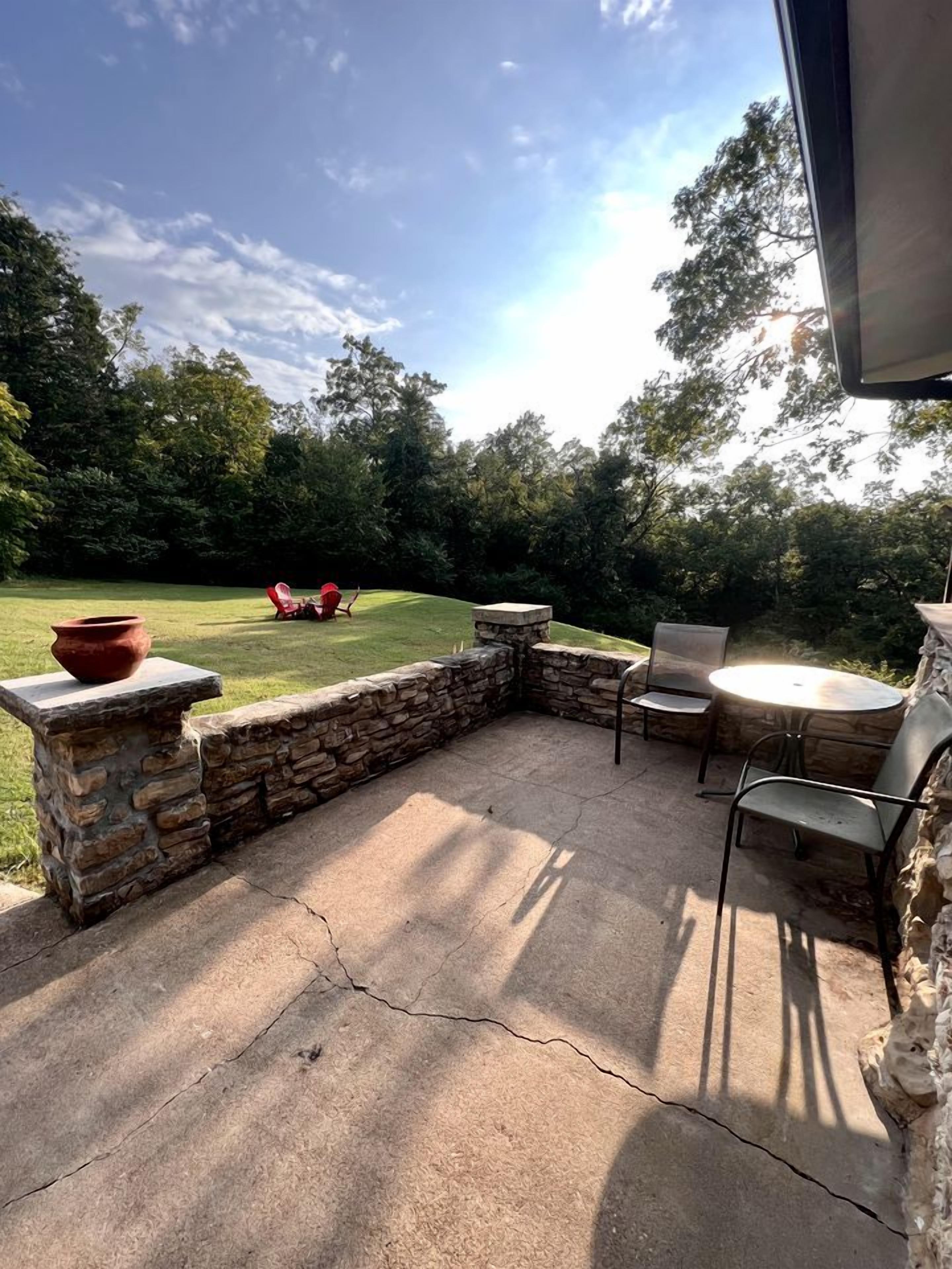 An outdoor patio area with stone walls, a round table, and two chairs.