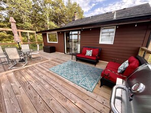 A wooden deck with a grill, outdoor seating, and a covered patio area. - Cozy Cabin Rental near Table Rock Lake in the Ozark Mountains, Missouri (Hollister)