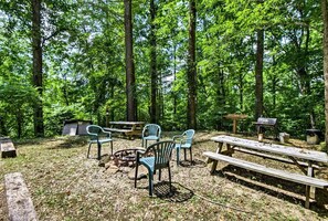 A campsite with picnic tables, chairs, a fire pit, and a grill.