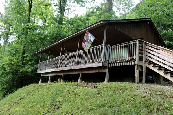 A wooden cabin with a balcony, surrounded by trees.