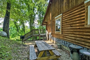 Eine Holzhütte mit Holzterrasse, Picknicktisch und Mülleimer.